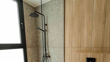 Un baño moderno con cabina de ducha de vidrio, inodoro y panel de pared de madera.