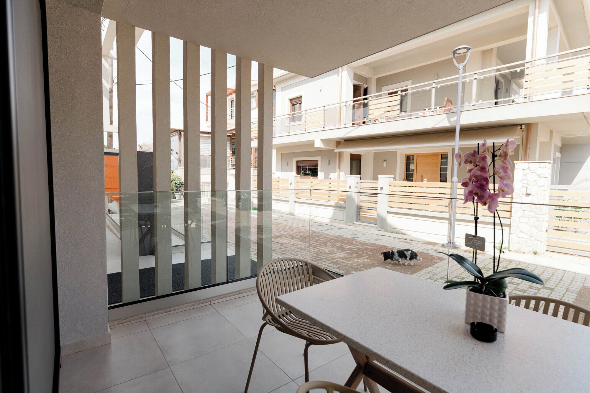 A modern apartment with a balcony, a dining area, and a view of neighboring buildings.