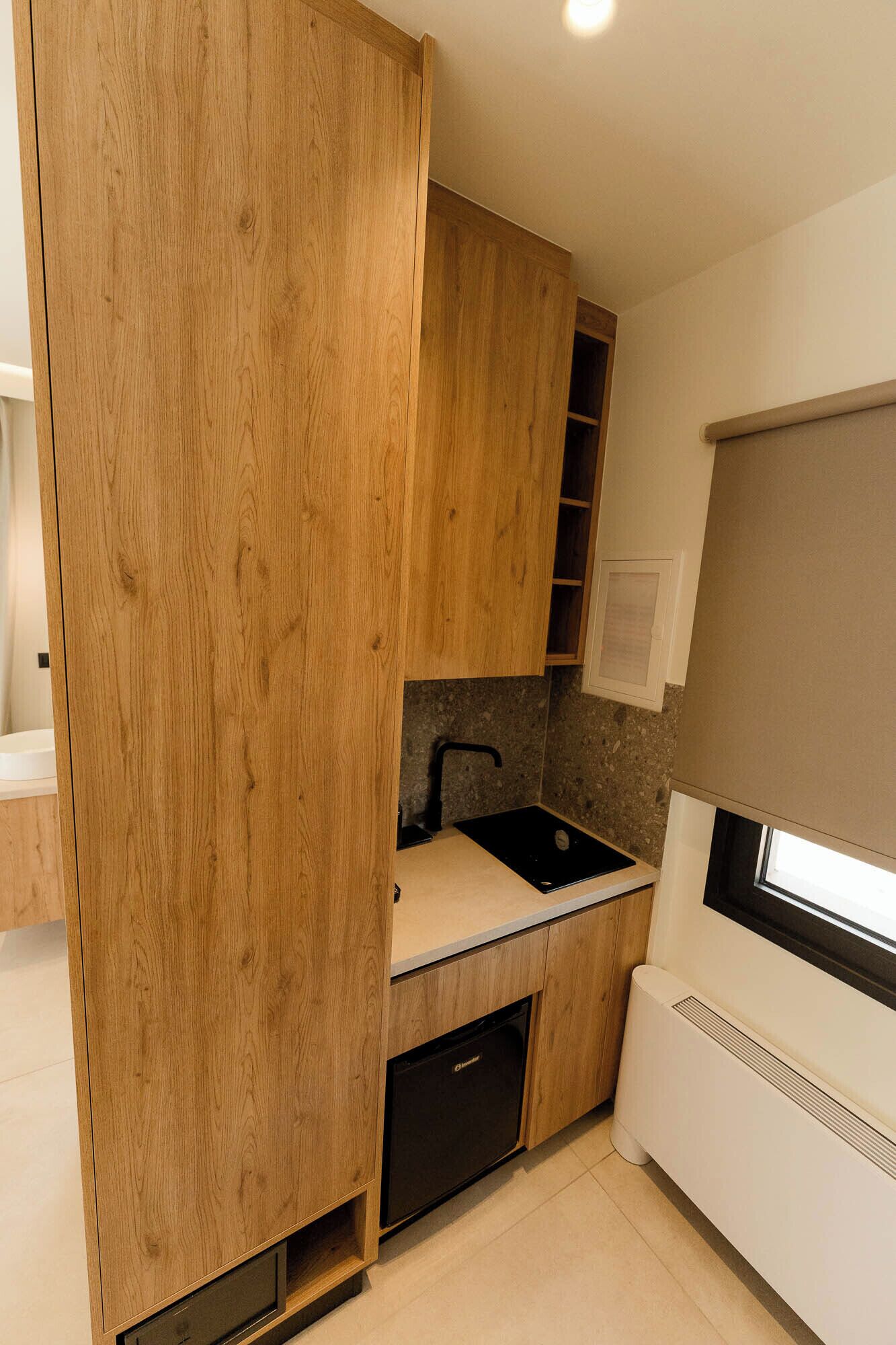 Una cocina moderna con armarios de madera, un lavamanos negro y un lavavajillas integrado.
