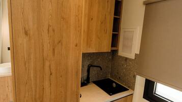 Una cocina moderna con armarios de madera, un lavamanos negro y un lavavajillas integrado.