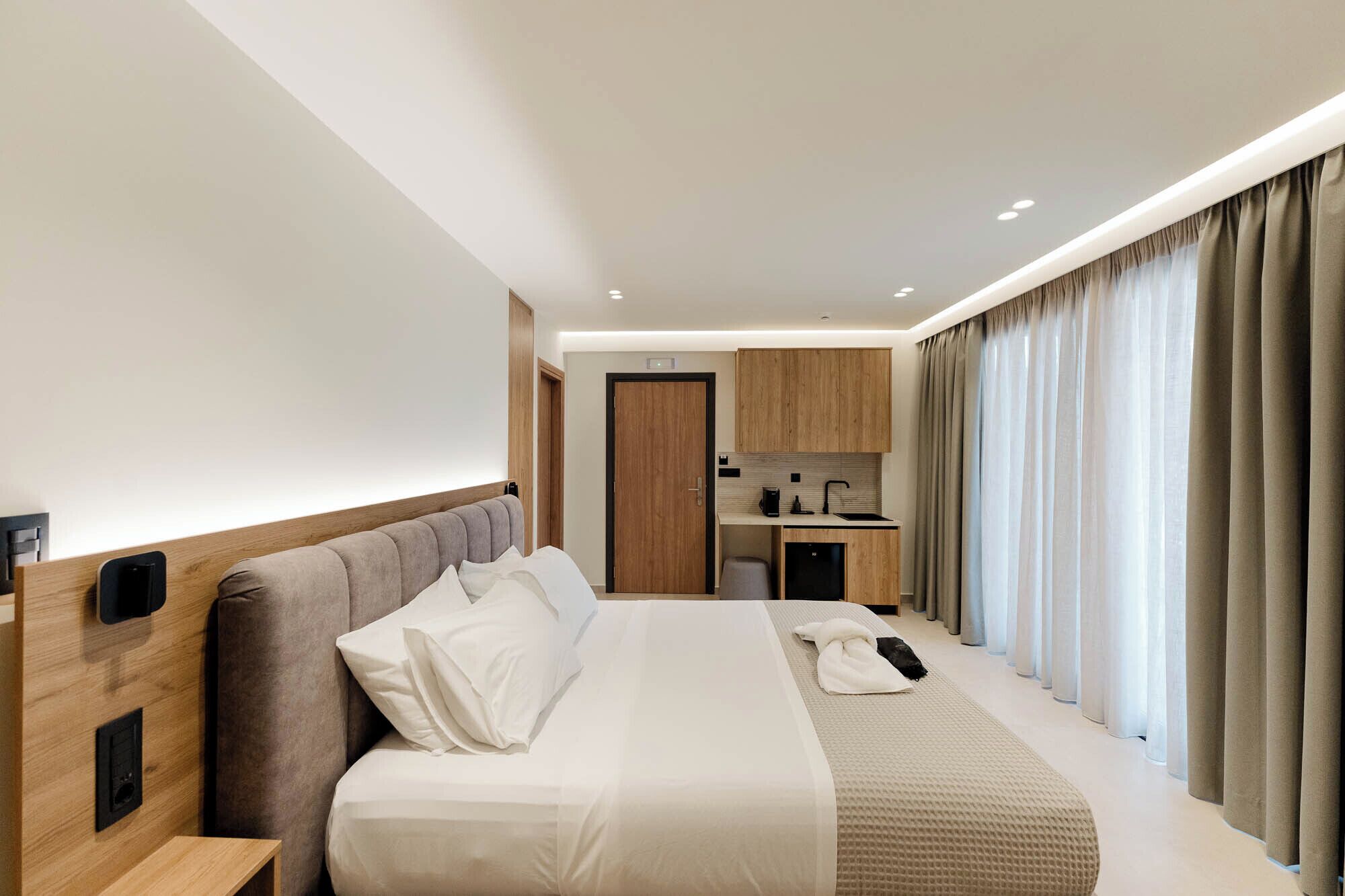 Una habitación de hotel con cama, una kitchenette pequeña y un baño.
