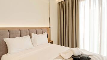 A hotel room with a bed, a nightstand, a lamp, and a window with curtains.