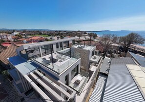 A modern building with a rooftop terrace, large windows, and a view of the sea. - Aetheria North (Amaliada)