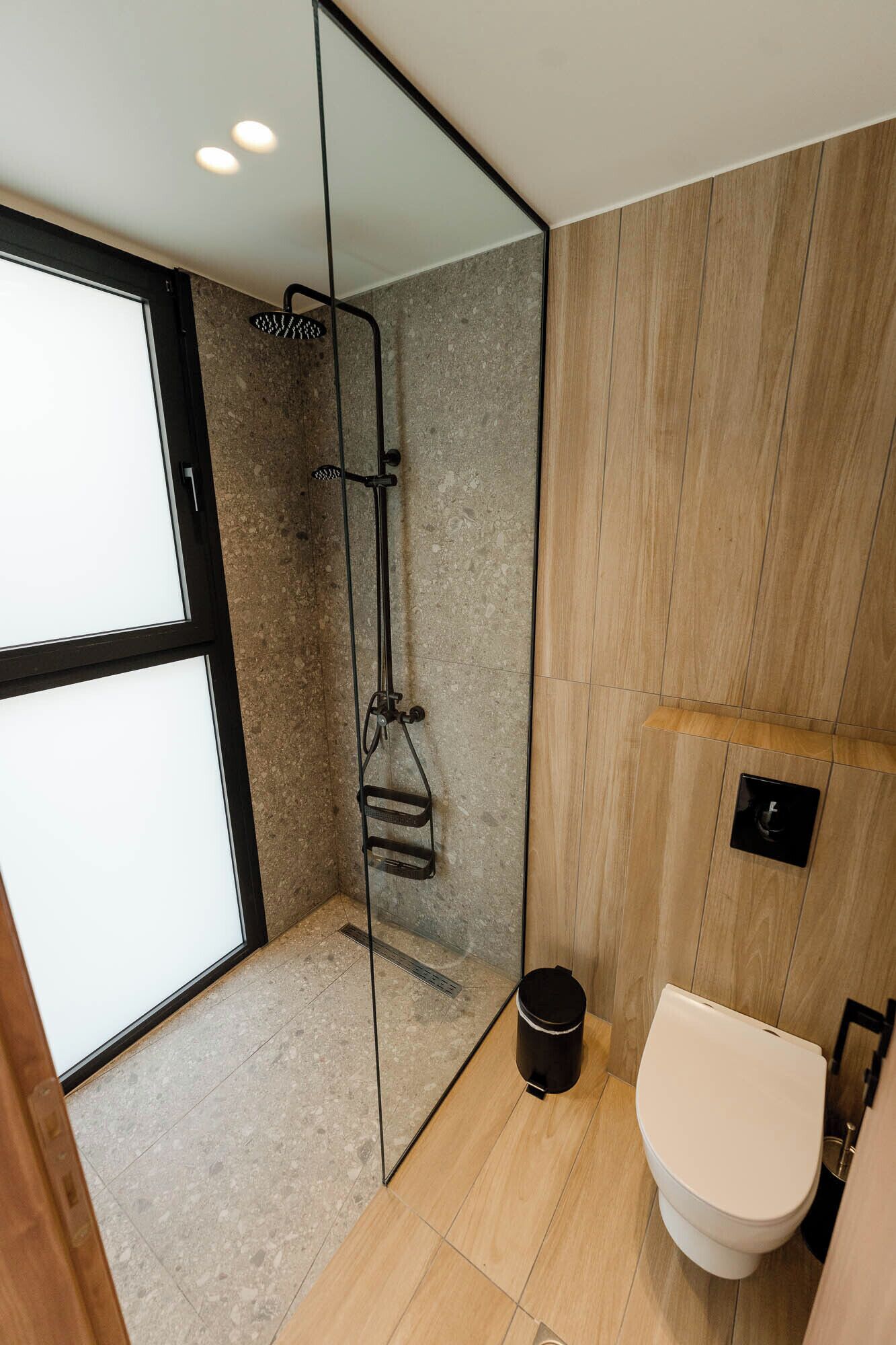 Een moderne badkamer met een douchecabine van glas, een toilet en een wastafel.