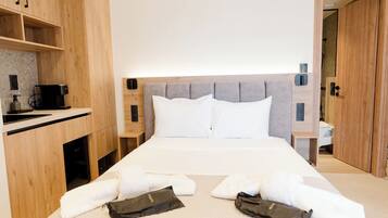 Une chambre d’hôtel avec un lit, une armoire en bois, une table de chevet avec une machine à café et une porte de salle de bain.