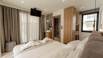 Una habitación de hotel moderna con una cama grande, televisión, baño con espejo y ventana.