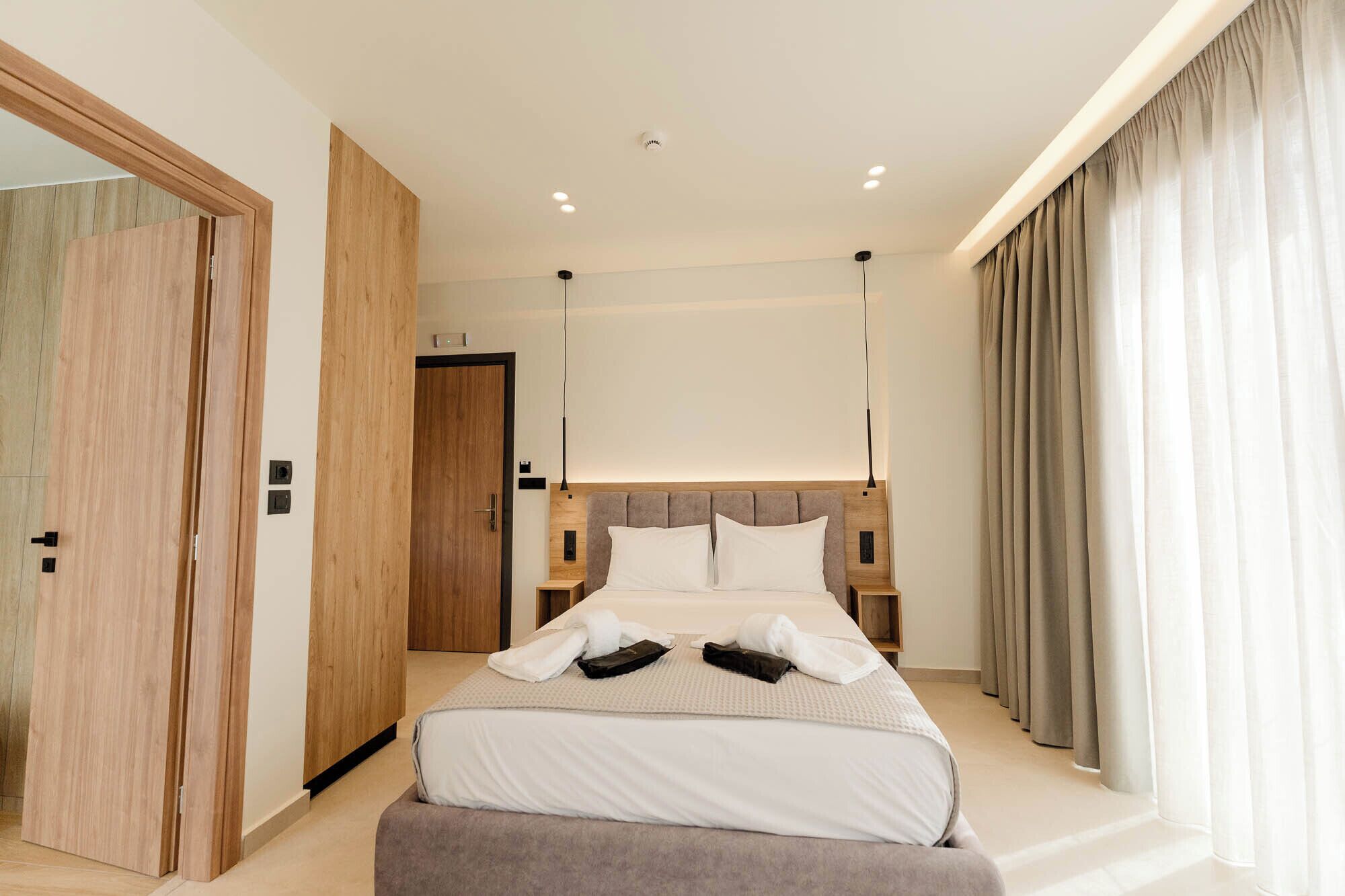 Una habitación de hotel moderna con una cama grande, un armario de madera y vistas al exterior.