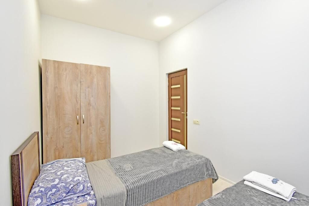 A small, single-bed room with a wooden wardrobe and a door with a handle.