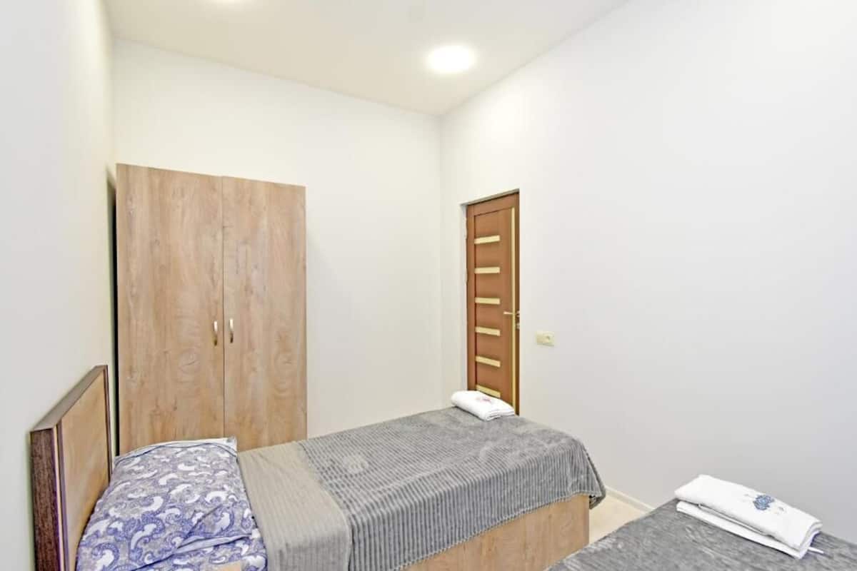 A small, single-bed room with a wooden wardrobe and a door with a handle.