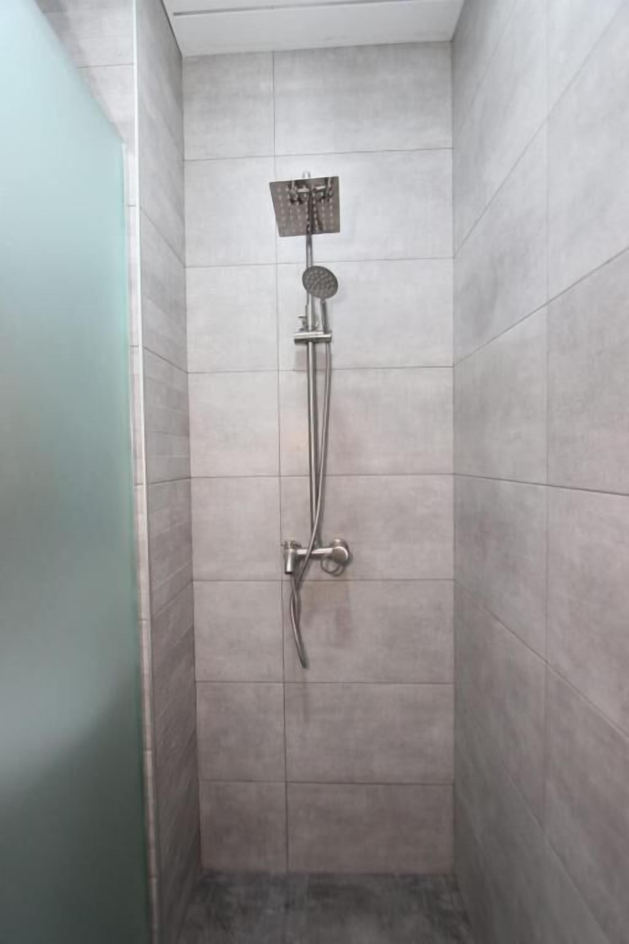 A shower with a handheld showerhead and a wall-mounted faucet.