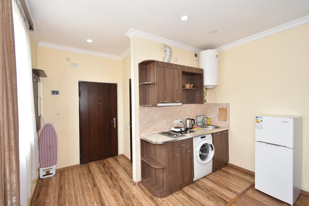 Una cocina compacta con muebles de madera, lavadora, refrigerador y una pequeña encimera.