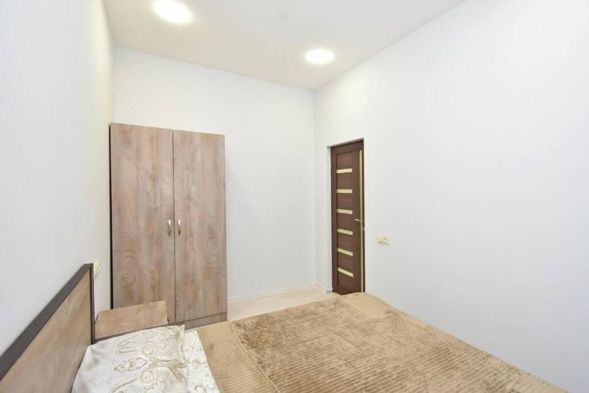 A bedroom with a bed, a wardrobe, and a door.