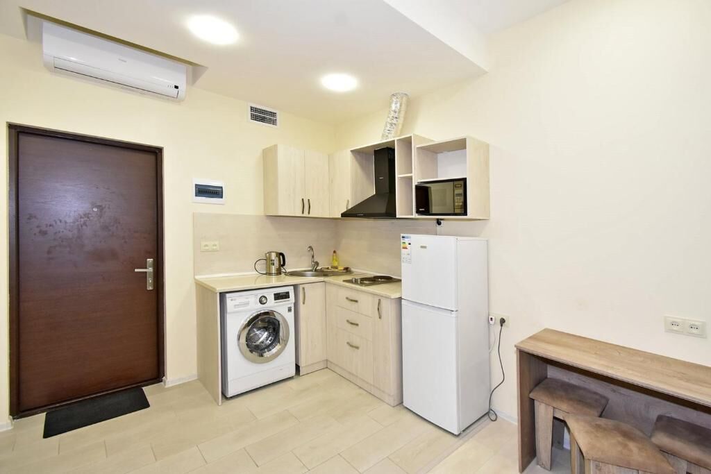 A compact kitchen with a washing machine, microwave, and a small dining area.