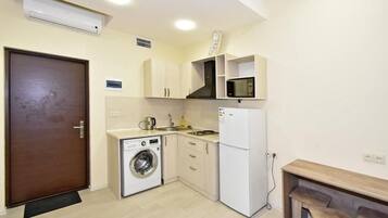 A compact kitchen with a washing machine, microwave, and a small dining area.