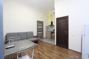 A compact living space with a sofa, dining table, chairs, a kitchen area, and a refrigerator. - Komitas Residence (Yerevan)