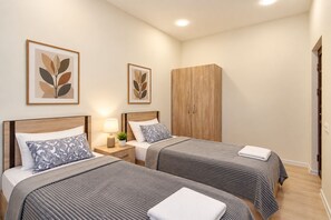 A hotel room with two beds, a wardrobe, and artwork on the walls.