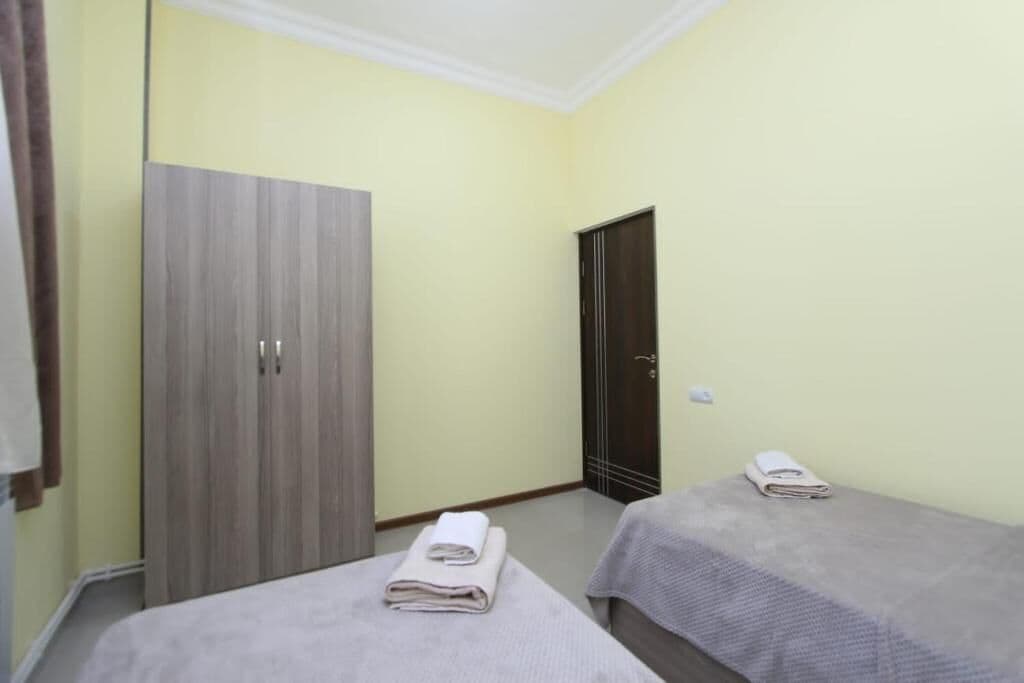 A room with two beds, a wardrobe, and a door.