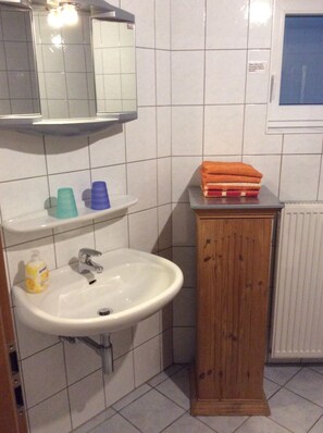 A bathroom with a white sink, a mirror above it, and a wooden cabinet. - Pure nature - relaxation in a quiet vacation apartment in the middle of the Harz Nature Park (Clausthal-Zellerfeld)