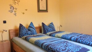 Un letto matrimoniale con biancheria a motivi, un comodino, una lampada e un quadro appeso al muro.