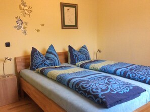 A double bed with patterned bedding, a bedside table, a lamp, and a framed picture on the wall. - Pure nature - relaxation in a quiet vacation apartment in the middle of the Harz Nature Park (Clausthal-Zellerfeld)