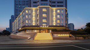 Um hotel moderno com entrada imponente, vários andares e fachada bem iluminada.