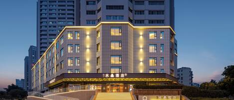 A modern hotel with a prominent entrance, multiple floors, and a well-lit facade.