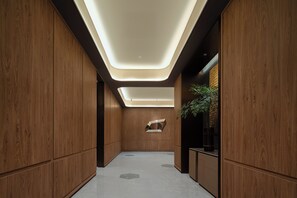 A modern interior with wooden paneling, recessed lighting, and a central plant.