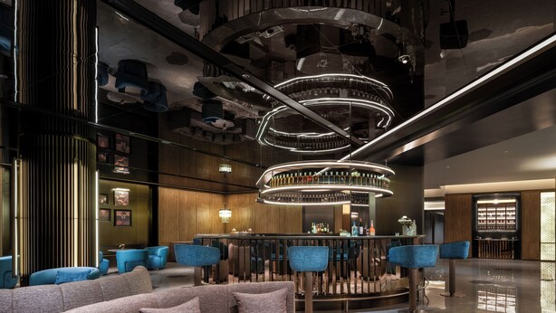 Uma área de bar moderna com luminária circular, assentos e balcão.