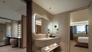 Casa de banho de hotel moderna, com lavatório, espelho e banco embutido.