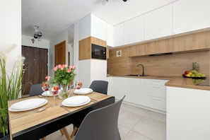 A modern kitchen with white cabinets, a wooden countertop, and a built-in oven. - Comfortable Studio with a Terrace | Near the Beach (Międzywodzie)