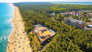 An aerial view of a beach resort with a sandy beach, dense forest, and a large building complex with multiple structures. - Comfortable Studio with a Terrace | Near the Beach (Międzywodzie)
