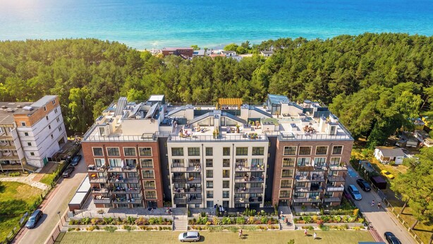 A multi-story building with balconies, a rooftop terrace, and a view of the sea. - Comfortable Studio with a Terrace | Near the Beach (Międzywodzie)