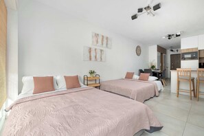 Een hotelkamer met twee bedden, een bureau en een kitchenette.