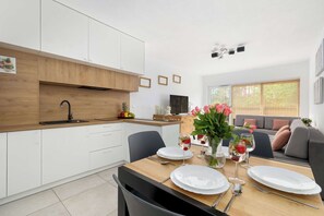Een moderne keuken met witte kastjes, een houten aanrecht en een eethoek gedekt met borden, glazen en een bloevas.