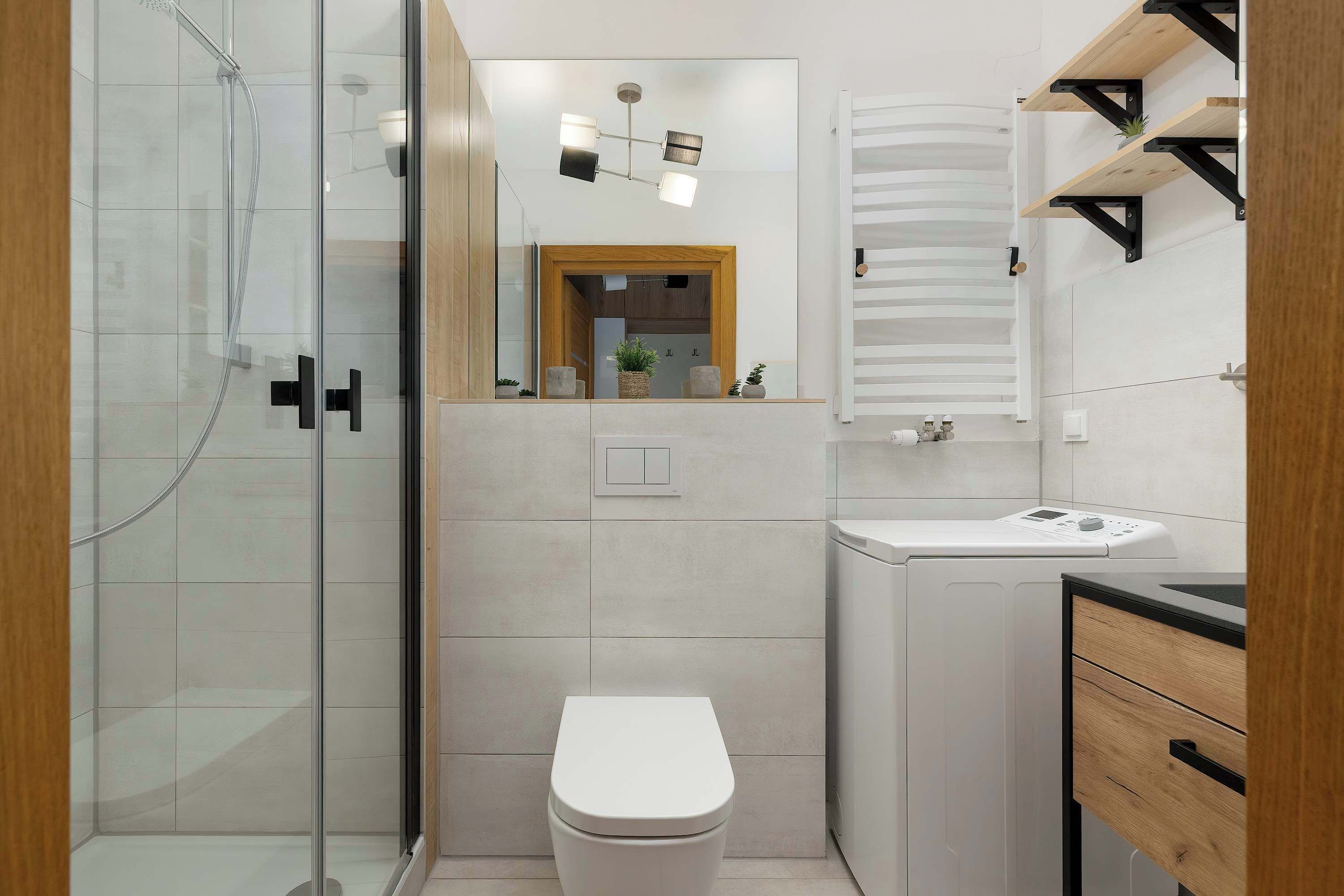 Ein modernes Badezimmer mit Duschkabine aus Glas, einer weißen Toilette, einem eingebauten Waschbecken und einem Spiegel darüber.