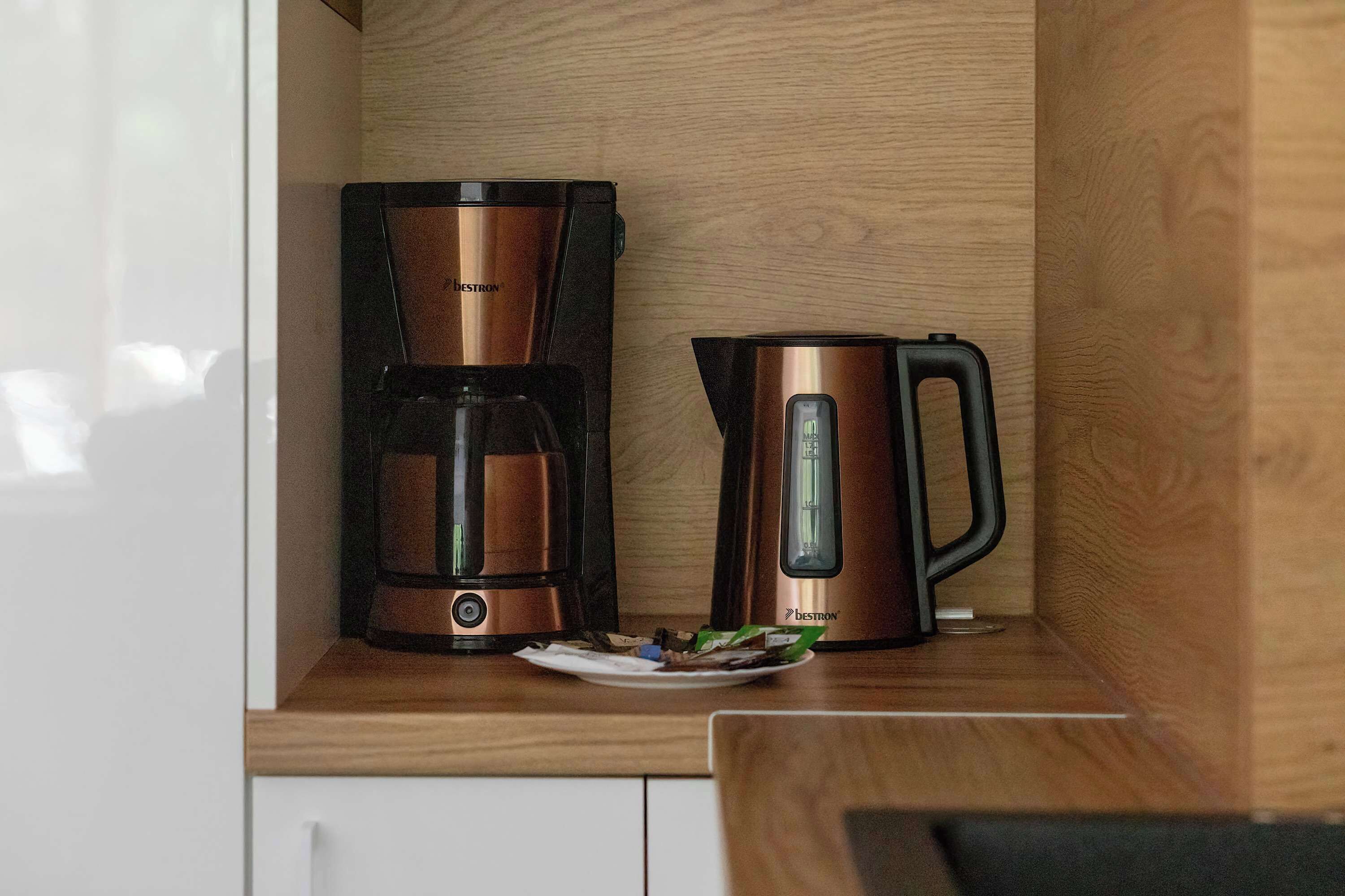 A kitchen with a coffee maker and a kettle on the counter.