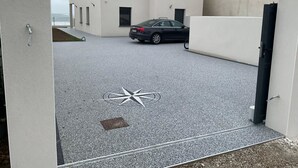 Uma área de estacionamento com um carro, um edifício com várias janelas e uma porta.