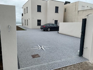 A parking area with a car, a building with multiple windows, and a door. - Magnificent sea View From This Apartment (Agde)