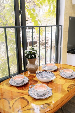 A round wooden table with a vase of white flowers and six patterned bowls and saucers. - Old Quarter Hoan Kiem Sunlit Artistic Home 2BR/1BA Apartment Central Hanoi (Hà Nội)