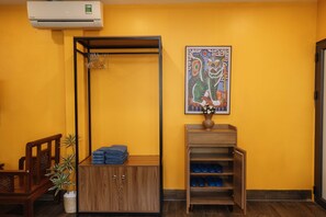 Ein Zimmer mit einem Holzschrank, einer kleinen Schuhablage, einer Wandklimaanlage und einem gerahmten Kunstwerk.
