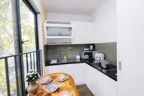 Eine moderne Küche mit weißen Schränken, einer schwarzen Arbeitsplatte und einem Fenster mit Blick auf Bäume.