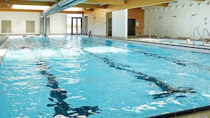 Ein Innenpool mit klarem Wasser, Holzbalken und Fliesenboden.