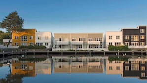 Eine Reihe moderner Gebäude mit Balkonen, die sich in ruhigem Wasser spiegeln.