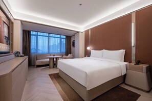 A modern hotel room with a large bed, a desk, a sofa, and a view of the city. - Crystal Hotel Wusi Square Wheat Island (Qingdao)