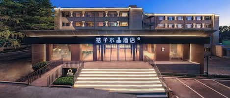 A hotel with a modern facade, a staircase leading to the entrance, and a signboard with Chinese characters.