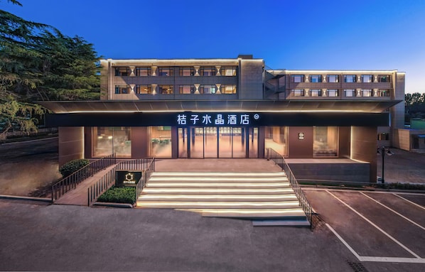 A hotel with a modern facade, a staircase leading to the entrance, and a signboard with Chinese characters.