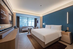 A hotel room with a large bed, a desk with a flat-screen TV, a sofa, and a window with curtains. - Crystal Hotel Wusi Square Wheat Island (Qingdao)