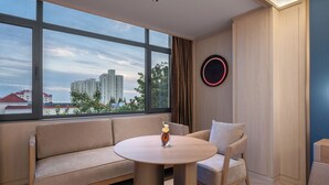 A modern room with a large window, a round table, a sofa, and a wall-mounted light fixture.