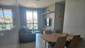 Una sala de estar moderna con comedor, ventanas amplias y vista a la ciudad.