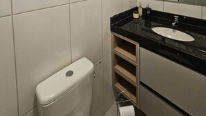 Un baño con inodoro, lavabo, espejo y ventana.